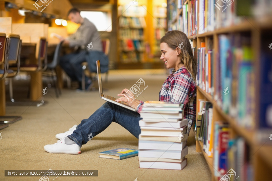 女学生坐在图书馆的地板上用电脑