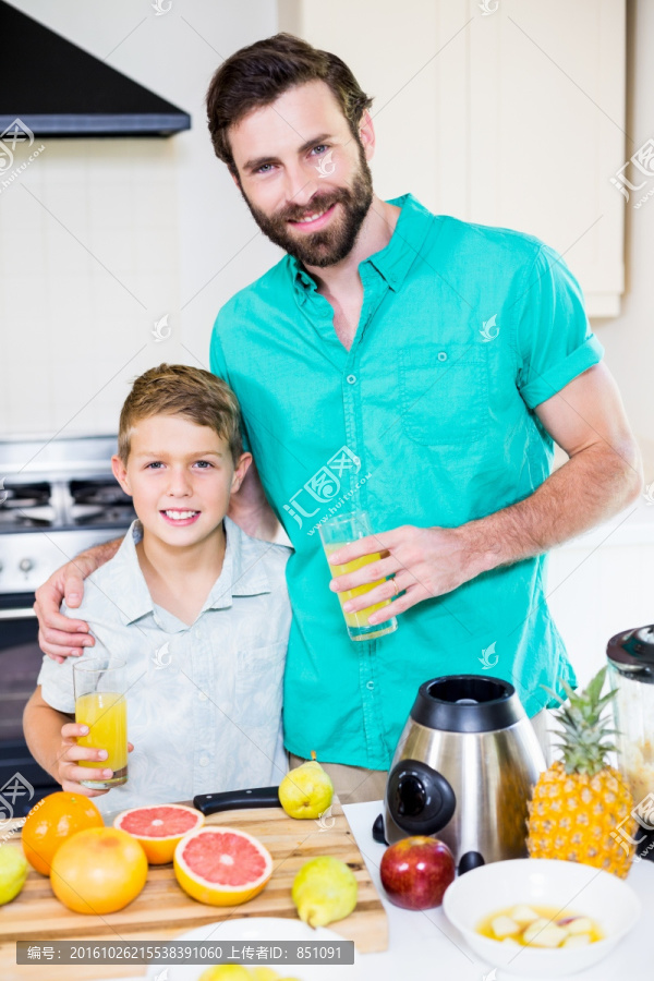 在厨房里拿着果汁的一对父女