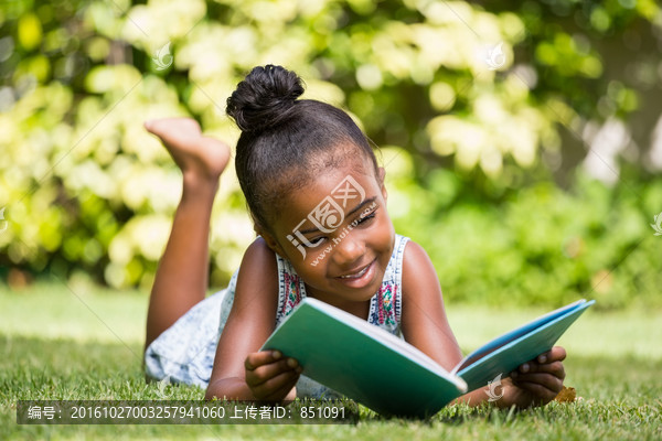 小女孩在公园读一本书