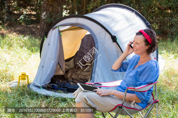 坐在帐篷旁打电话的女人