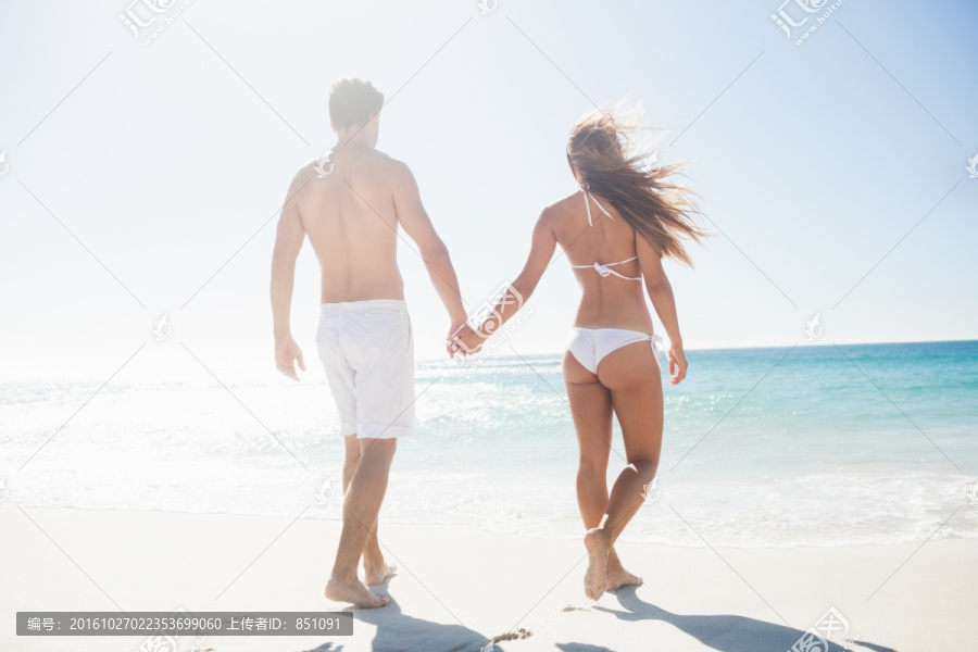 牵着手走在海边的情侣