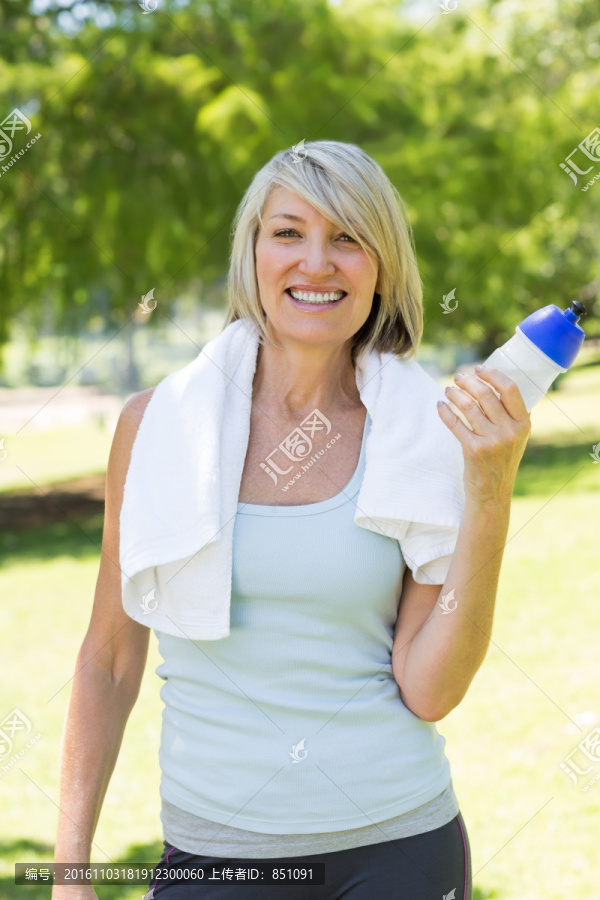 微笑的女人在公园里拿着水瓶