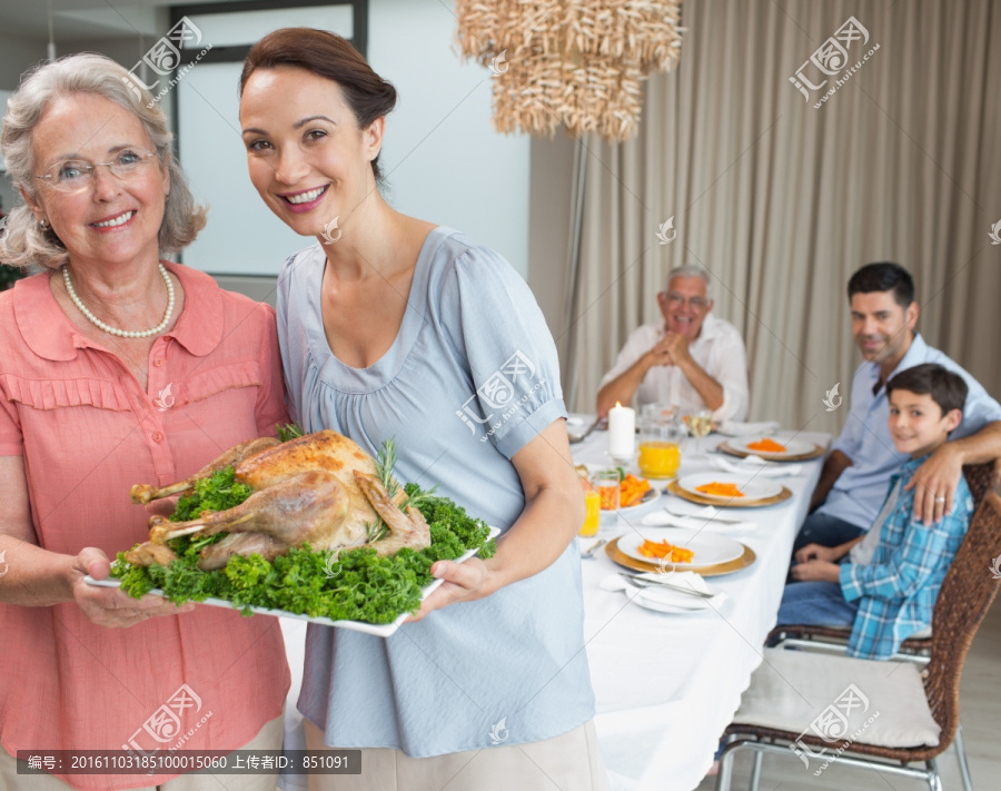 拿着一盘烤火鸡的祖母和母亲