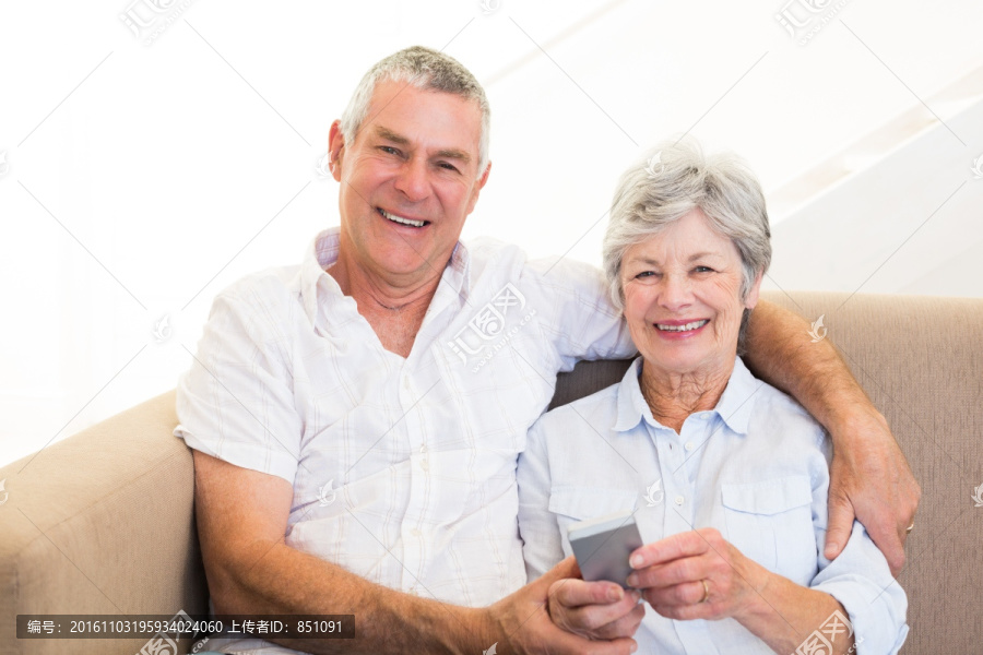 坐在沙发上玩手机的老夫妇