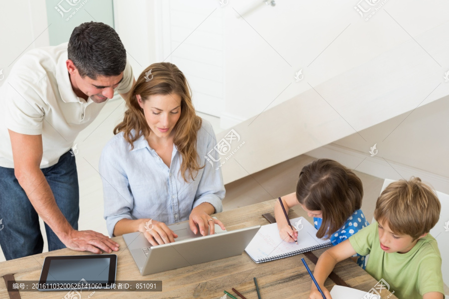 在客厅用电脑的父母和画画的兄妹