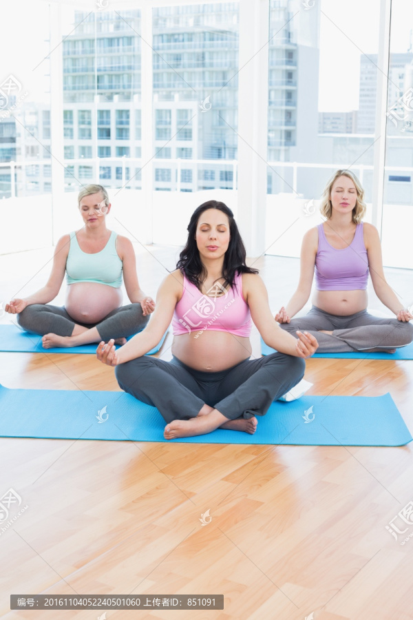 盘腿坐在瑜伽垫上冥想的孕妇