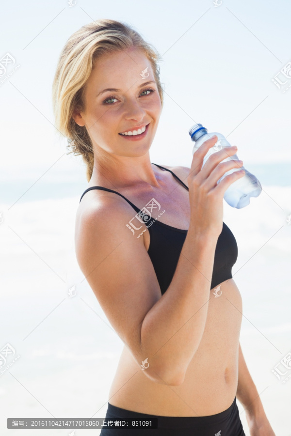在沙滩上喝水的女人