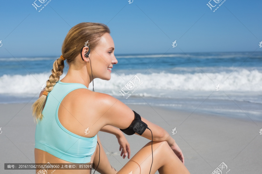 坐在海滩上听歌的女人