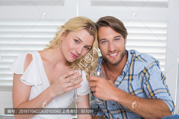坐在地板上喝白葡萄酒的年轻夫妇