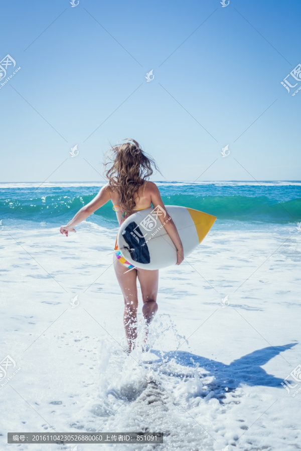 拿着冲浪板奔向大海的女人