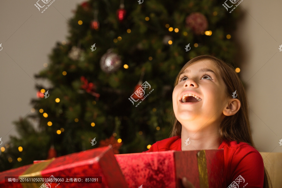 抬起头的小女孩拿着圣诞礼物
