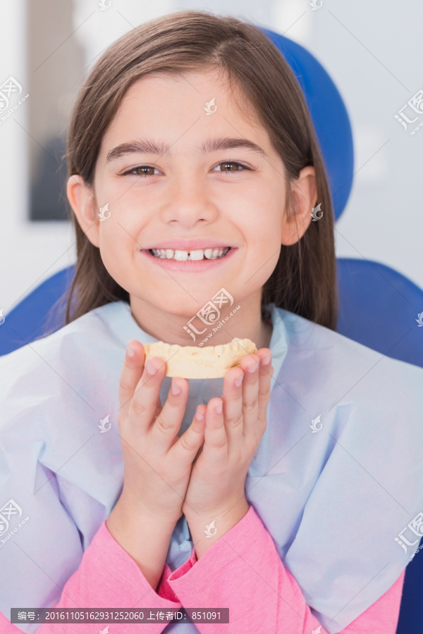 微笑着拿着牙齿模型的病人