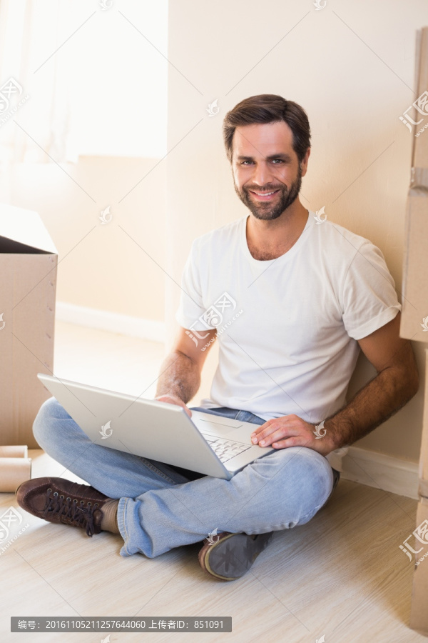 坐在地板上使用笔记本电脑的男人