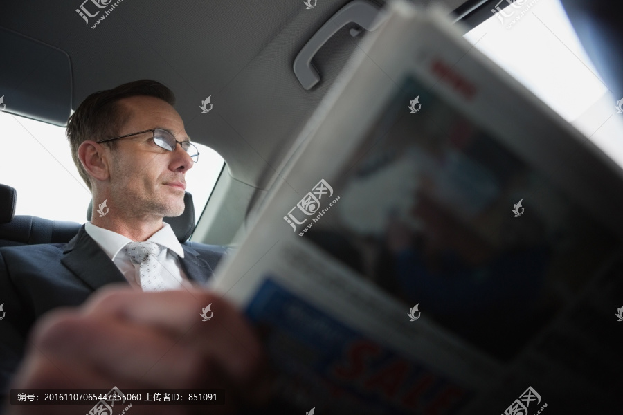 坐在车上看报纸的商务男人