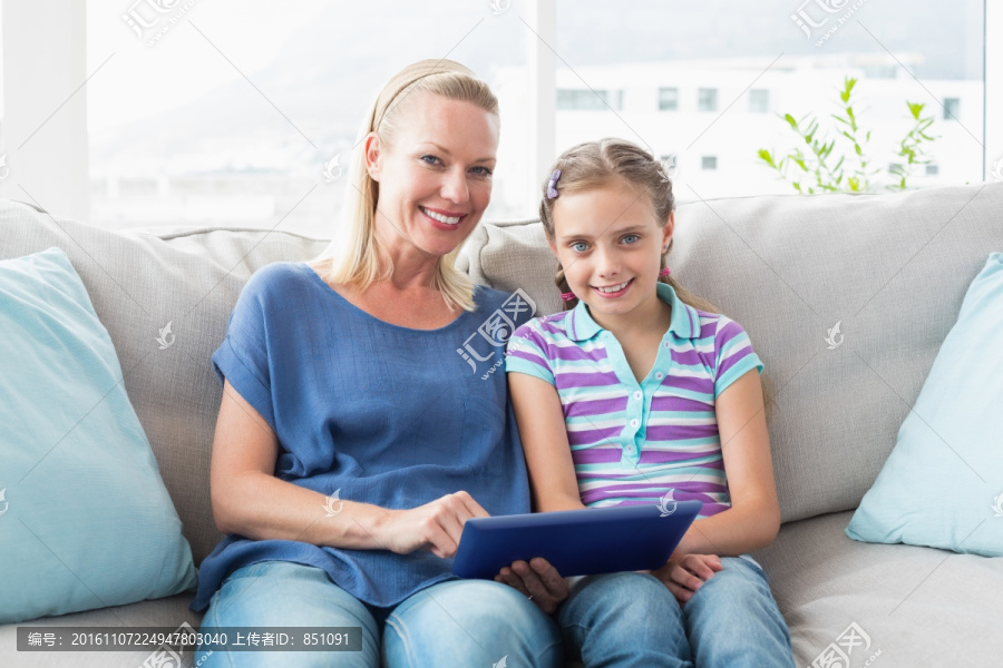 坐在沙发使用平板电脑的母女