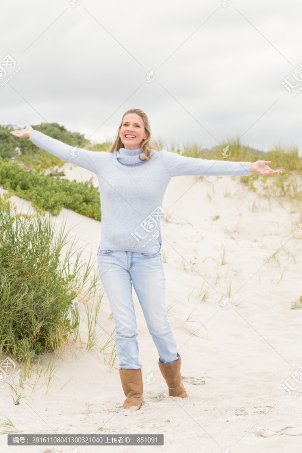 女人站在沙滩上张开双臂