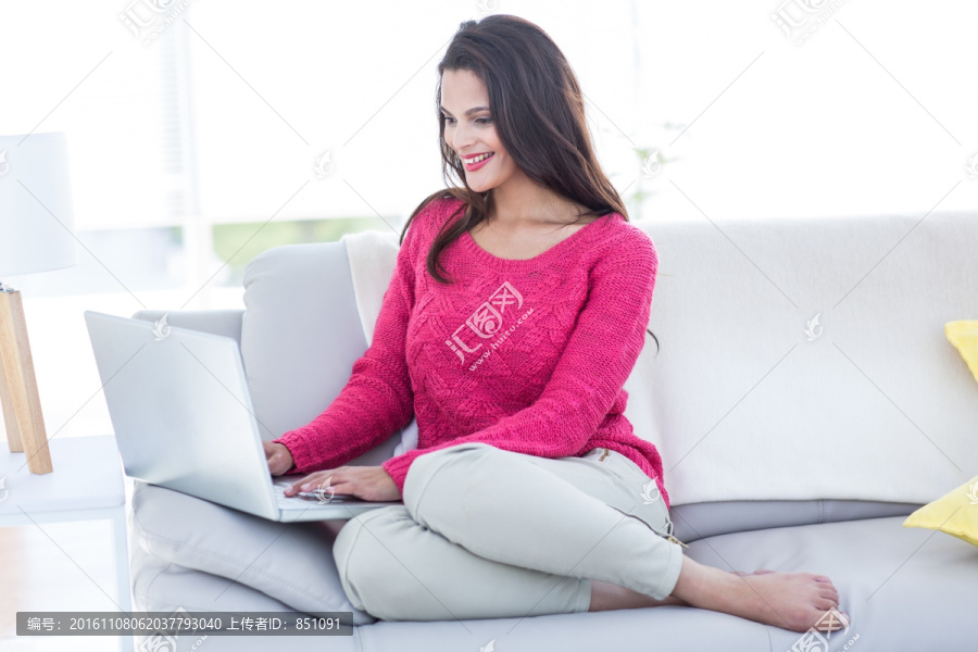 坐在沙发上使用电脑网购的女人