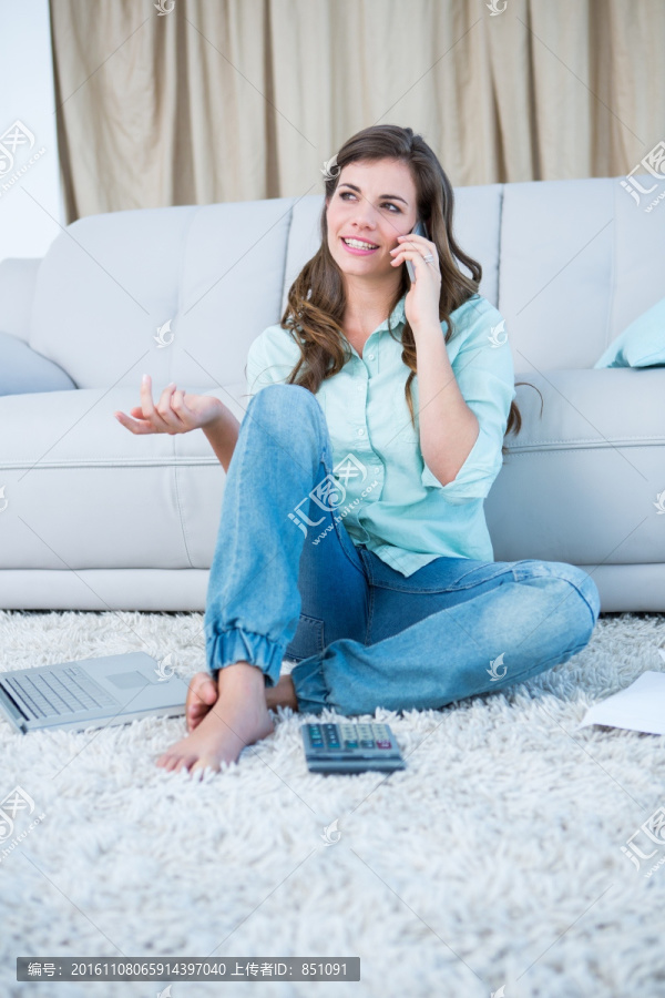 坐在地毯上使用手机打电话的女人