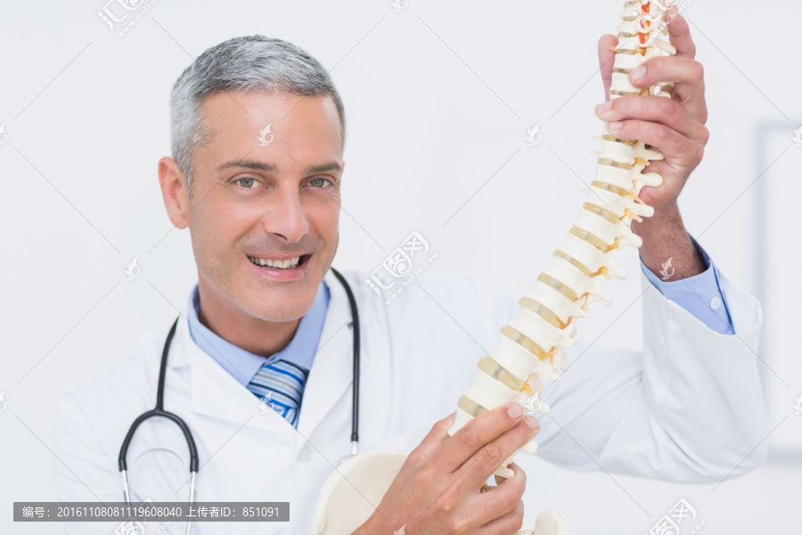微笑着拿着脊柱模型的医生