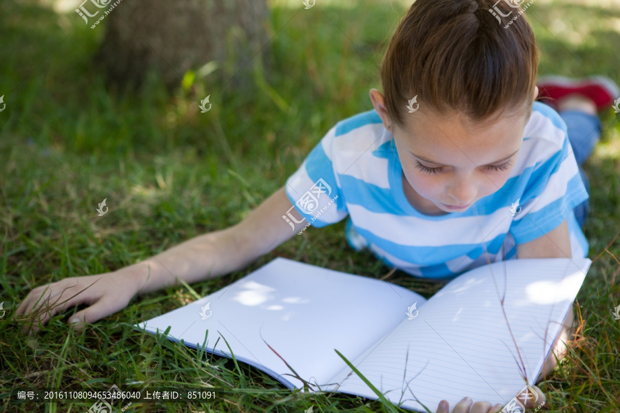 趴在草坪上看书的小女孩