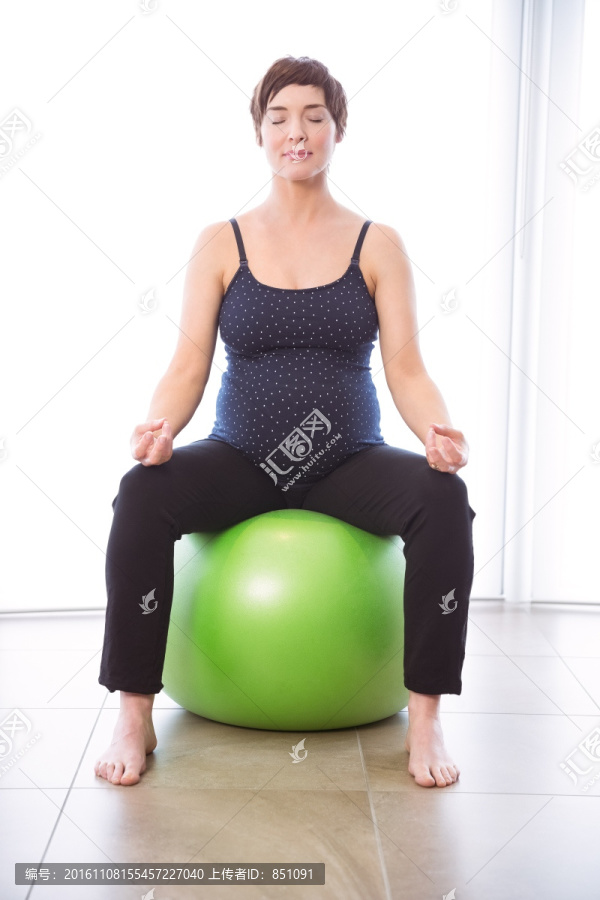 坐在健身球上的孕妇