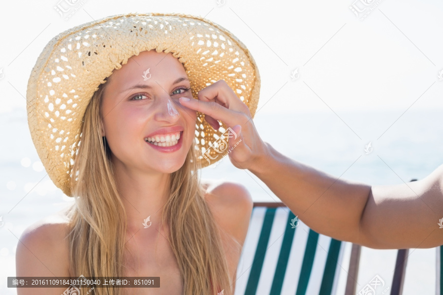 微笑的女人脸上涂着防晒霜