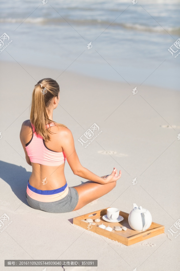 盘腿坐在沙滩上的女人