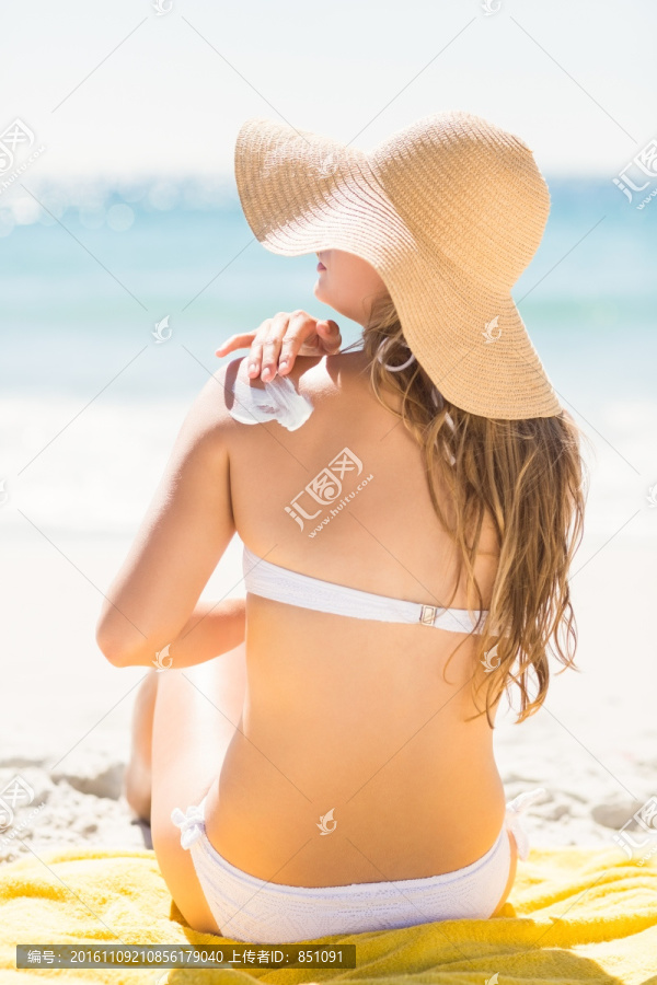 坐在沙滩涂防晒霜的女人
