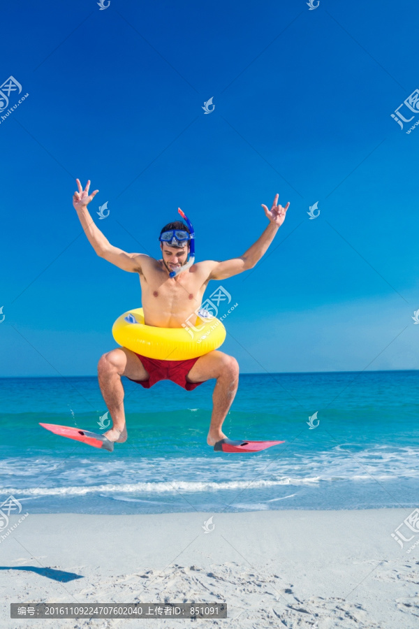 穿着脚蹼在沙滩上跳跃的男人