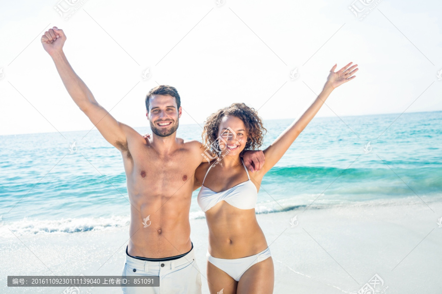 在海边举起手臂的夫妇