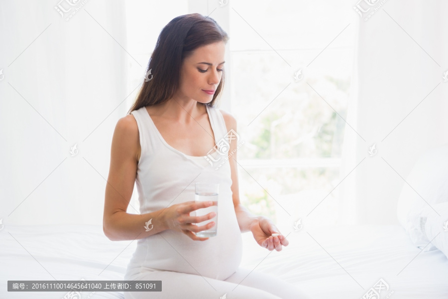 孕妇坐在床上服用维生素