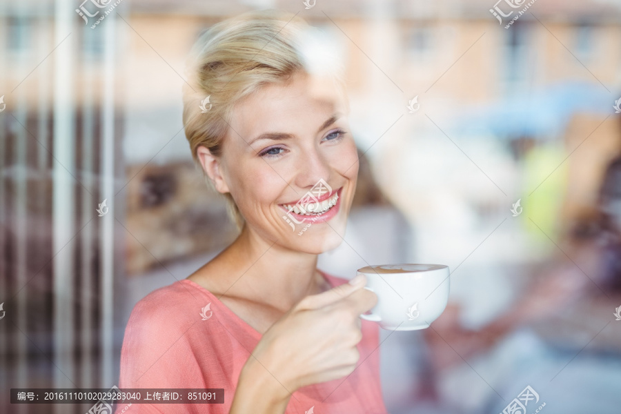 快乐的金发女人在喝一杯咖啡
