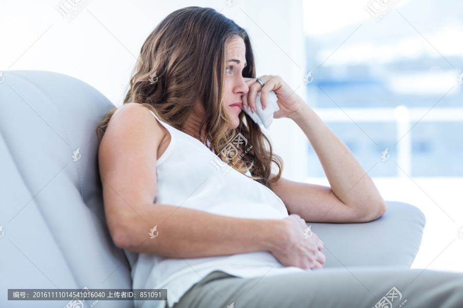 伤心的孕妇坐在家里的沙发上
