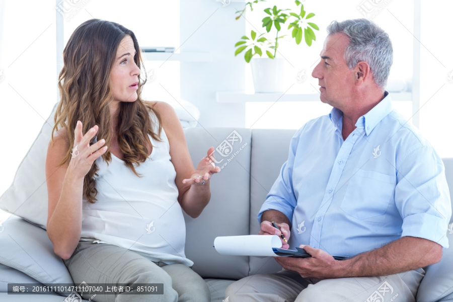 坐在沙发上与心理医生交谈的孕妇