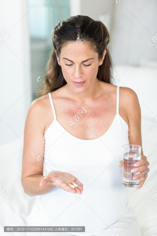 坐在床上吃抗生素的孕妇