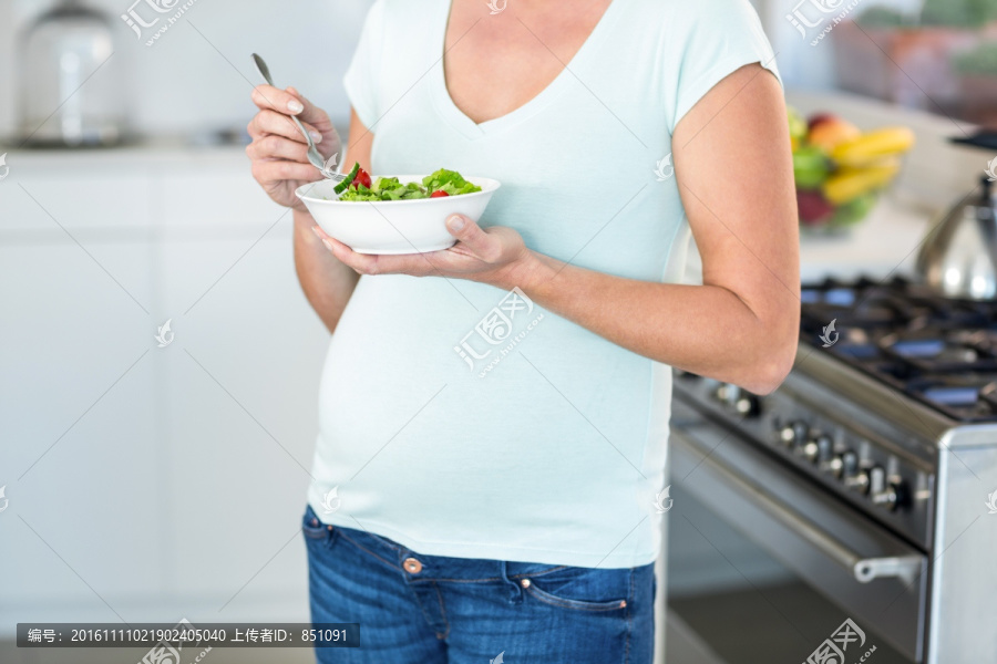 在吃蔬菜沙拉的孕妇