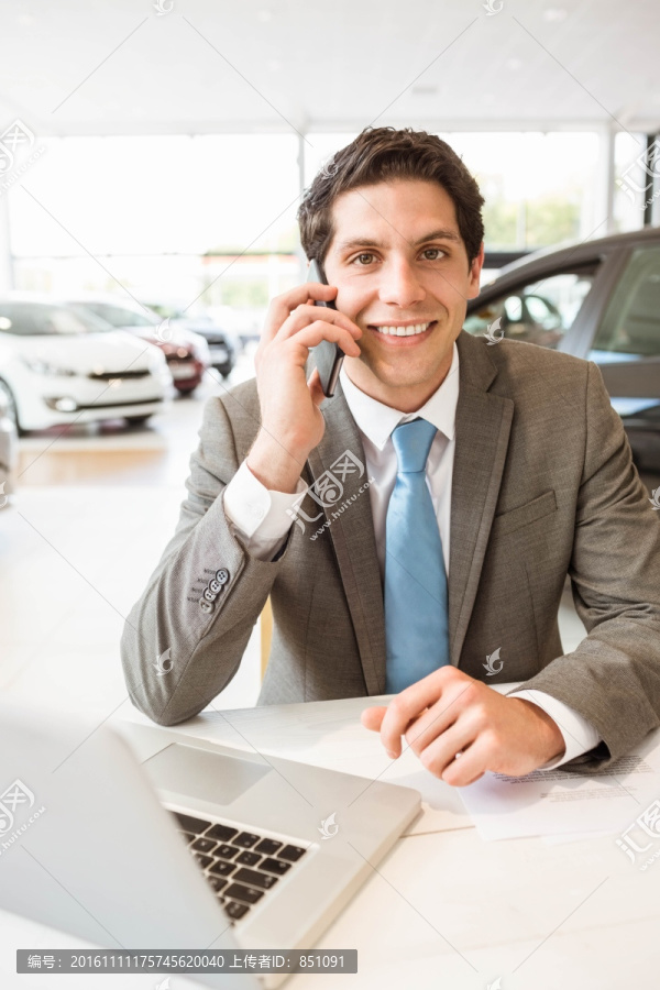 在汽车销售厅里打电话的男销售员
