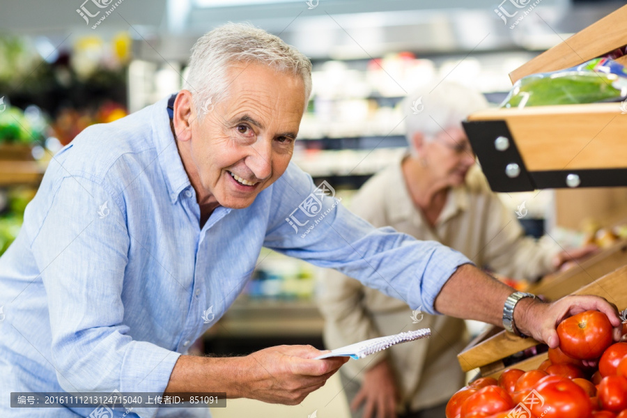 在超市里选购蔬菜的老人