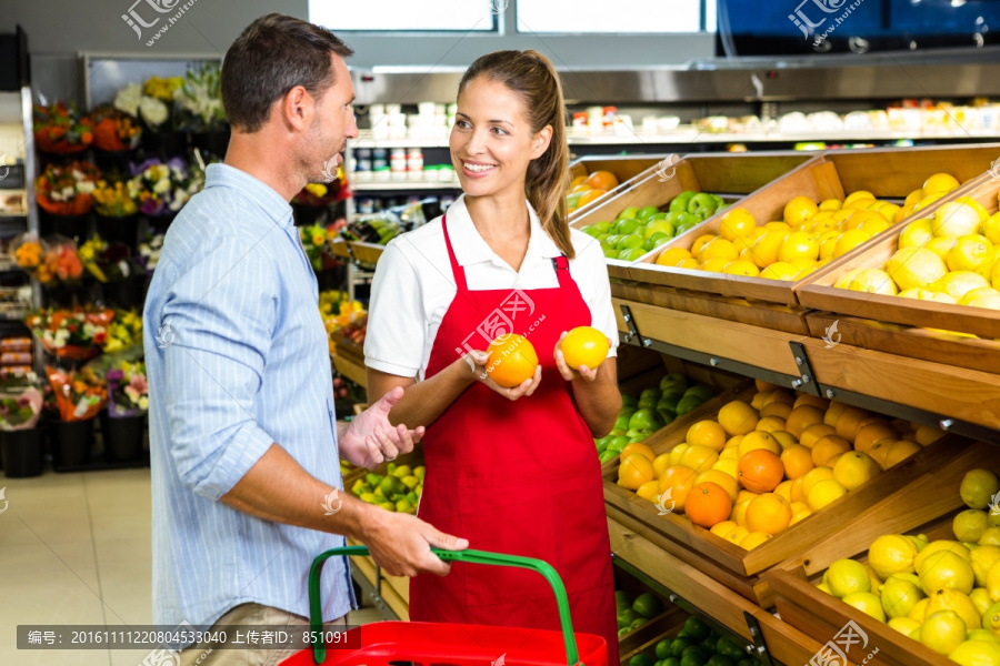 在超市里向顾客介绍水果的女员工