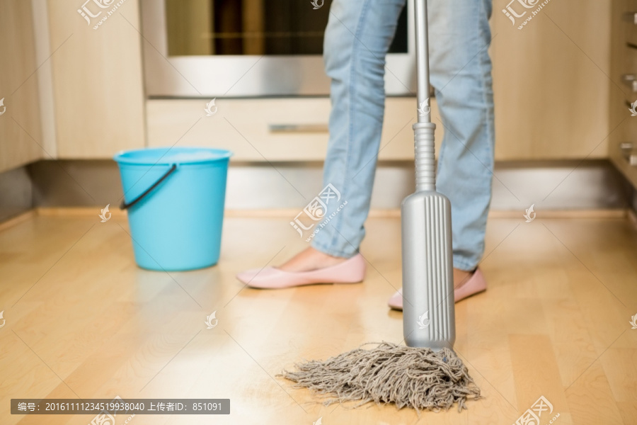 用拖把清洁厨房地板的女人