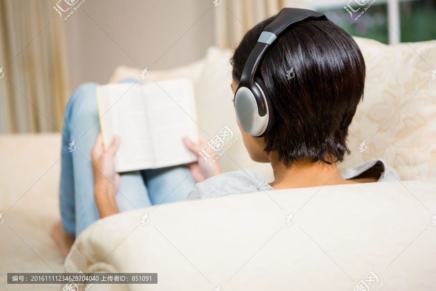 躺在沙发上听歌看书的女人