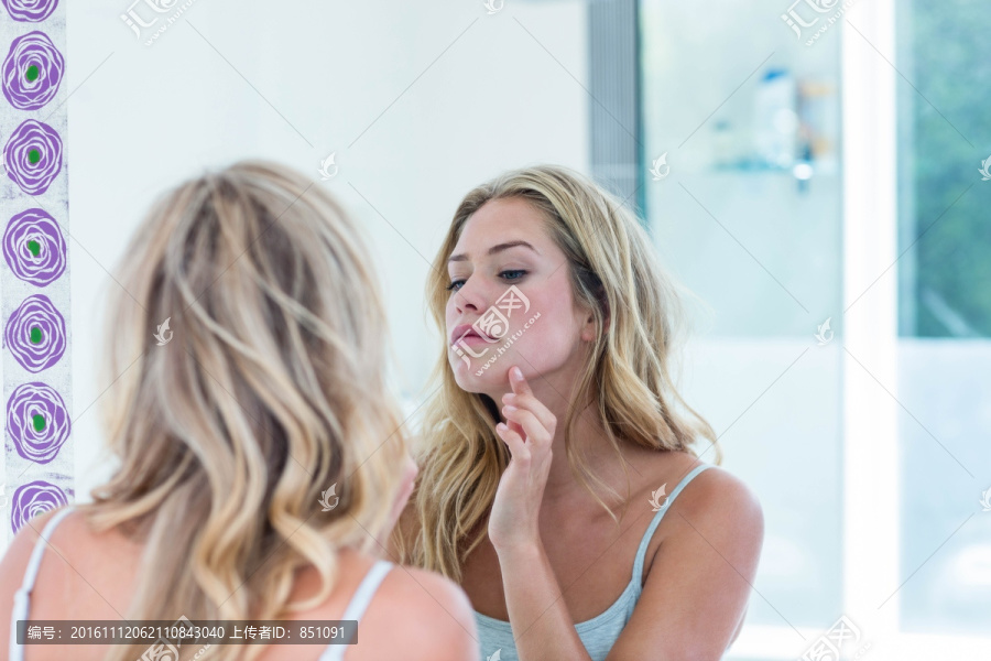 在照镜子看下巴的金发女人