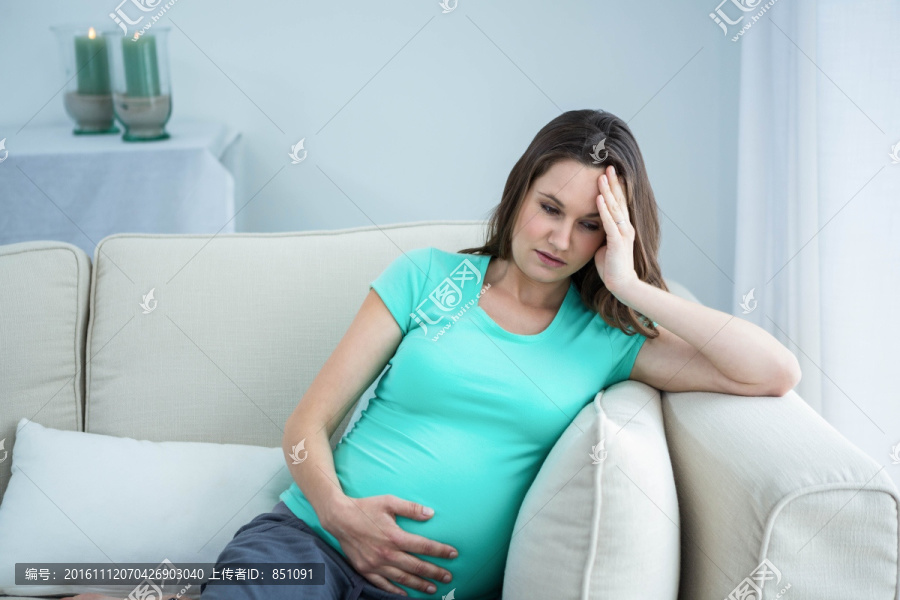 坐在沙发上头痛的孕妇