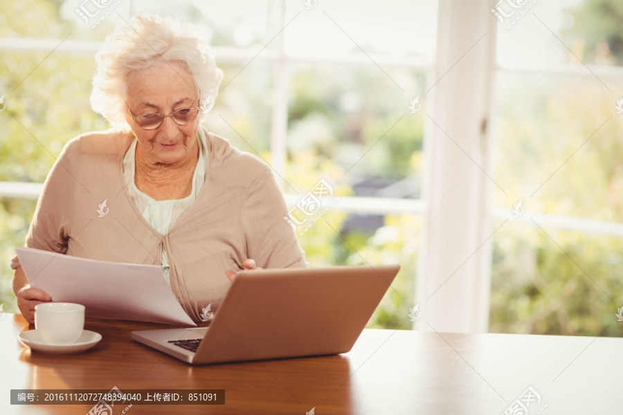 在用笔记本电脑处理文件的老太太