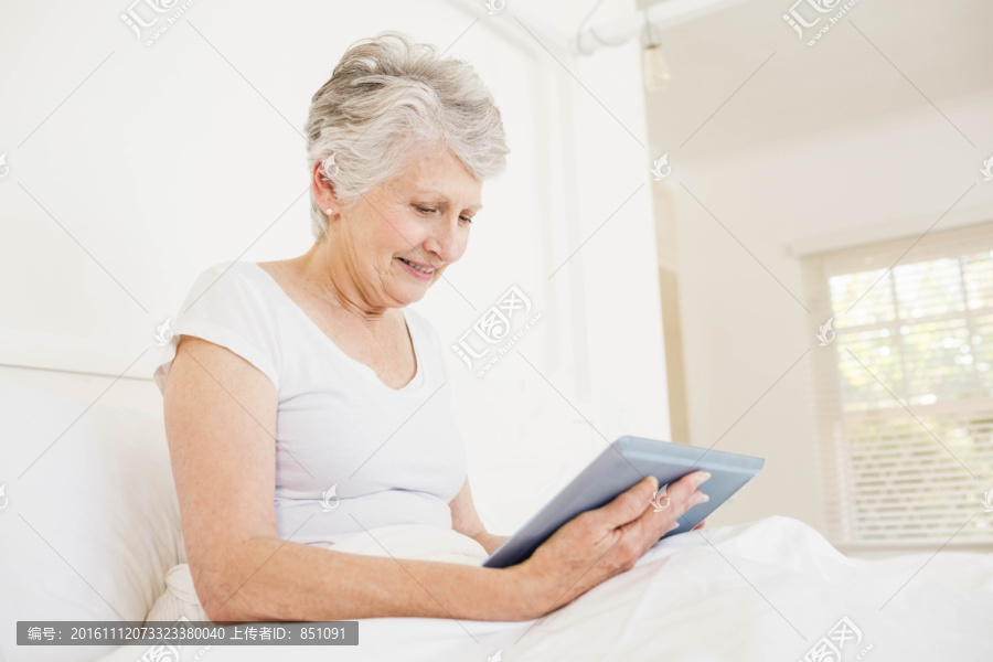 微笑的老太太在使用平板电脑