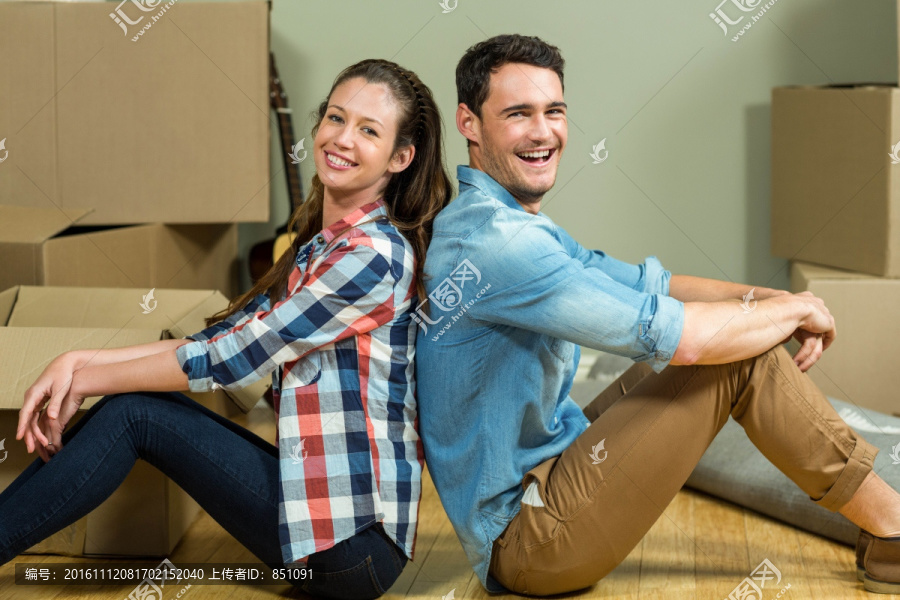 坐在新房子地板上的一对夫妇
