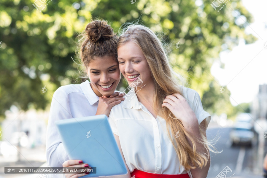 在街上用平板电脑的两个女人