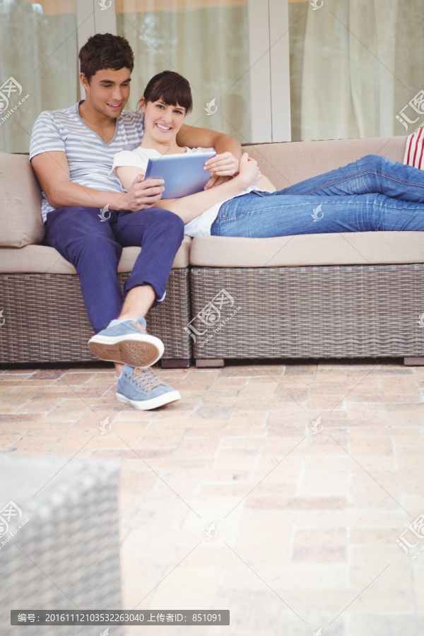 坐在沙发上使用平板电脑的夫妇