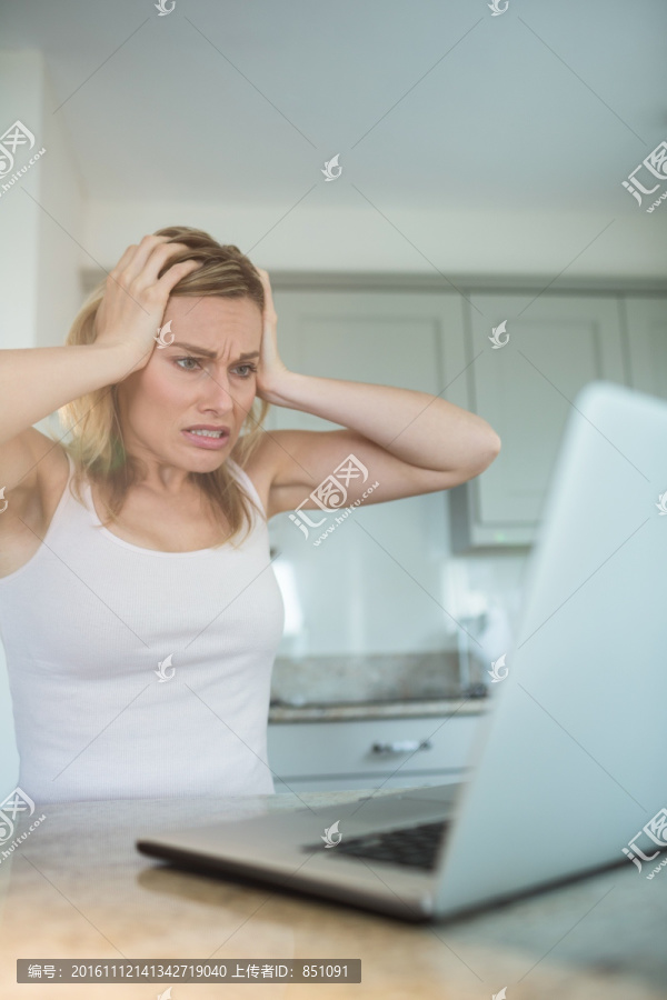 烦躁的女人在家里看笔记本电脑
