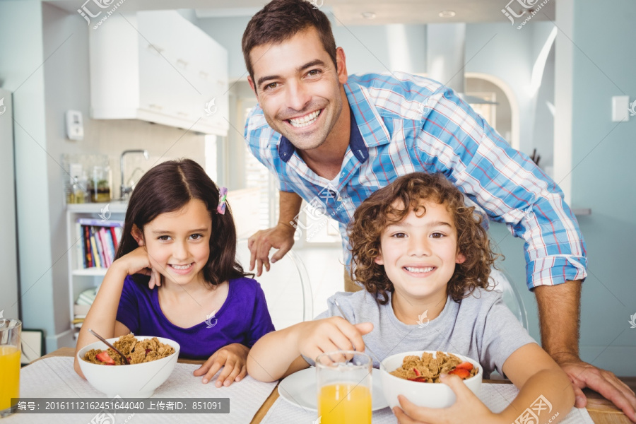 微笑的父亲在陪孩子在餐桌前吃饭